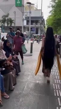 Une jeune fille indonésienne marche dans les rues de Jakarta en tenue traditionnelle